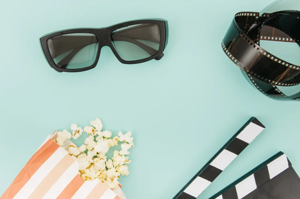 Retro sluneční brýle na stole s filmovou klapkou a kinovstupenkami