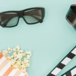 Retro sluneční brýle na stole s filmovou klapkou a kinovstupenkami